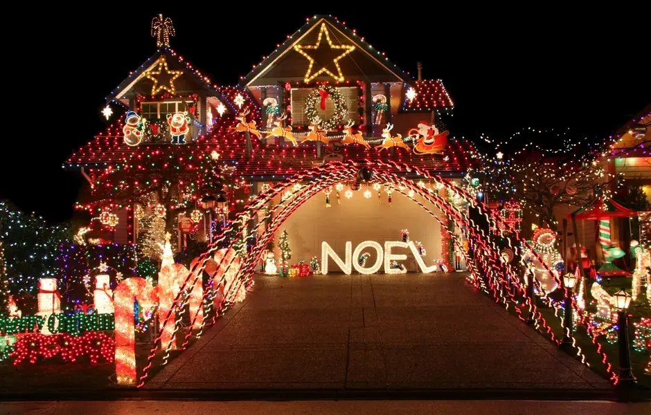 House roofline and arch covered in installed Christmas lights at night
