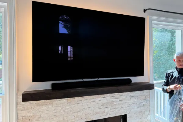 Large flat screen TV mounted flush on a living room wall above a soundbar