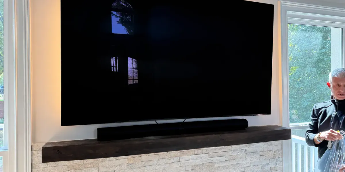 Large flat screen TV mounted flush on a living room wall above a soundbar